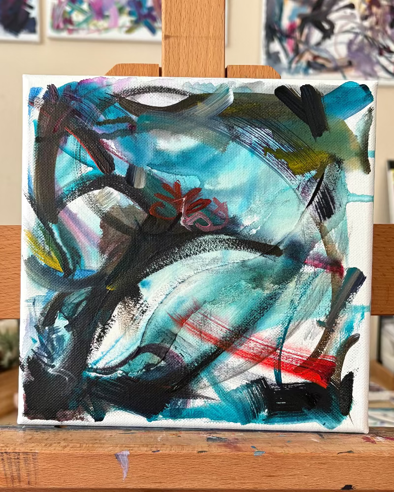 Abstract painting on an easel with other artworks in the background