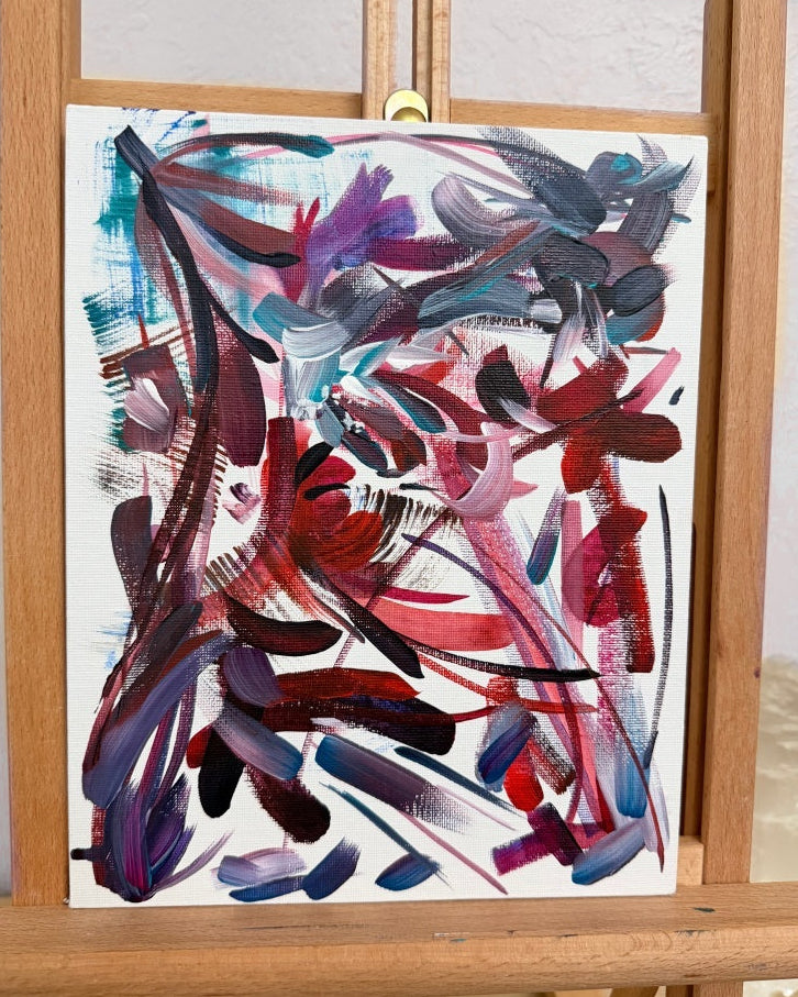 Abstract painting on a white canvas mounted on a wooden easel.