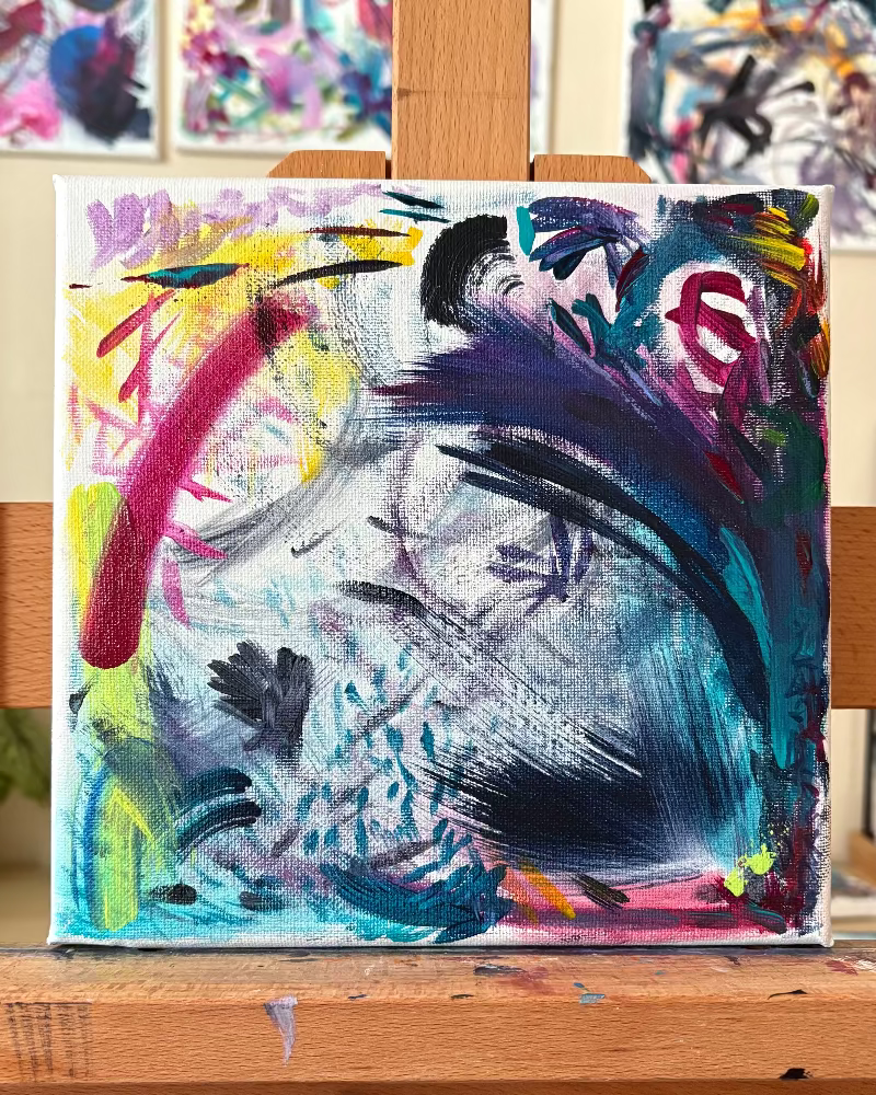 Abstract painting on a wooden easel with other artworks in the background