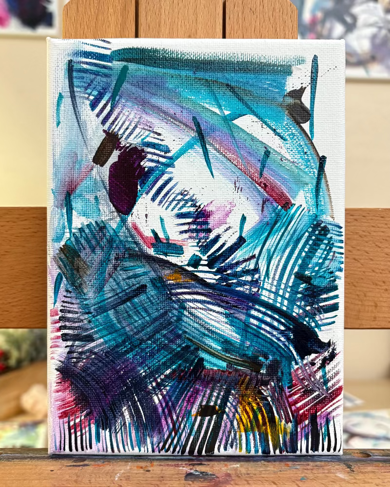 Abstract painting on a small canvas with a wooden easel.